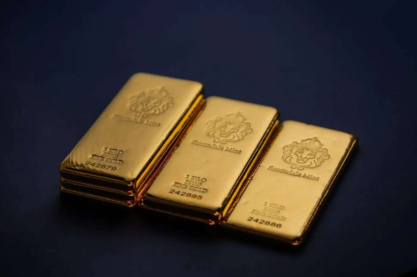 Three one-kilo fine gold bars laid side by side, serial numbers legible