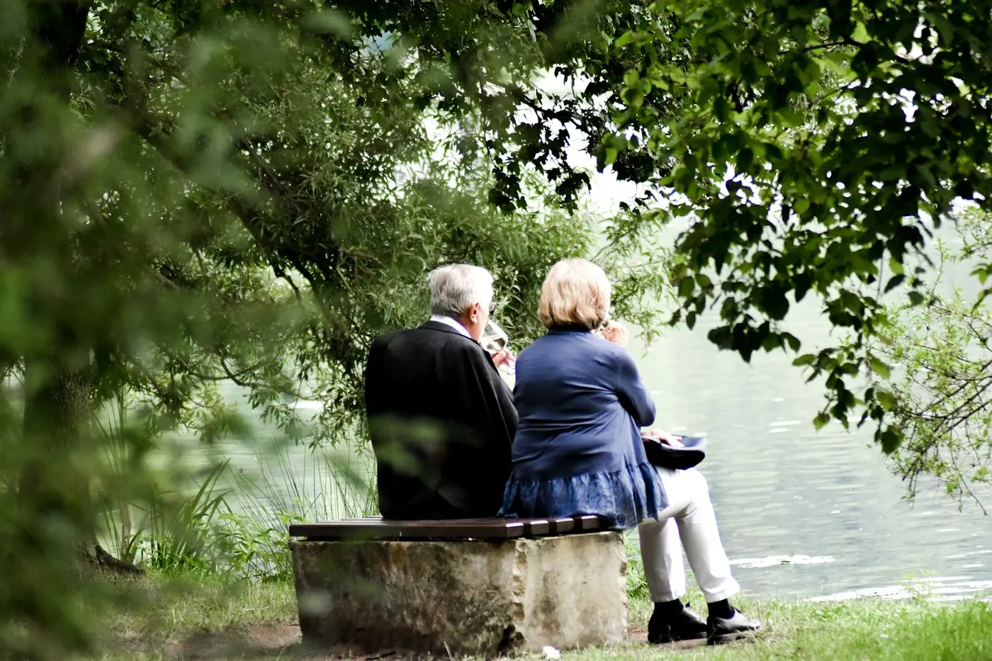 Two people sitting together on a quay, looking out over the water