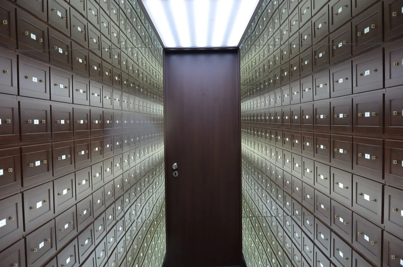 A corridor of numbered safe-deposit boxes receding to a door